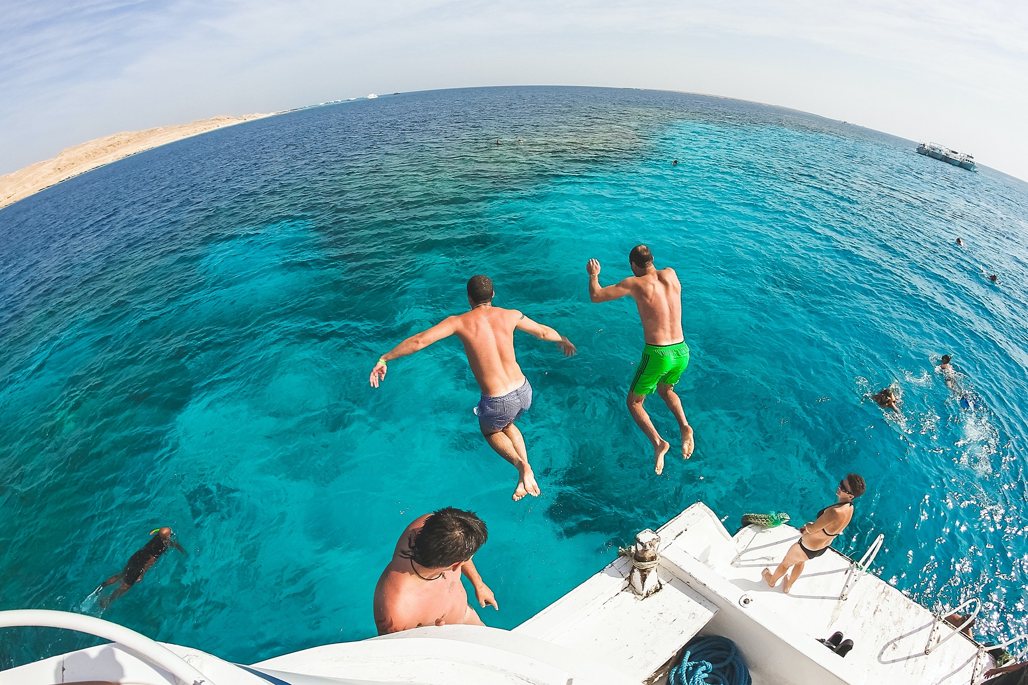 two-men-jump-into-the-sea-from-a-yacht-friends-are-having-fun-on-vacation-